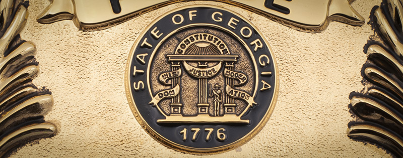 Georgia State seal in gold on a badge for Henry County Police Department